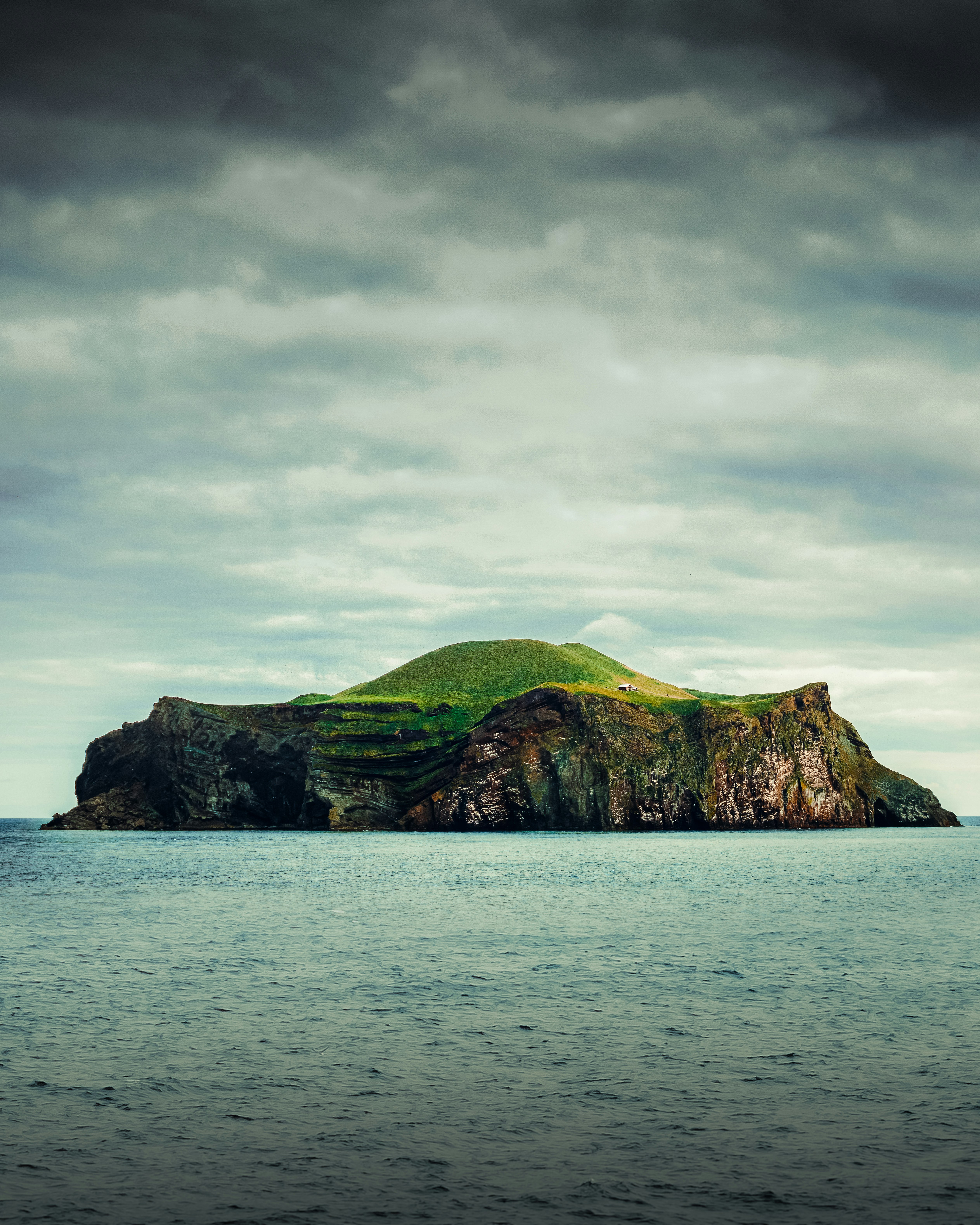 green and brown mountain beside body of water under cloudy sky during daytime